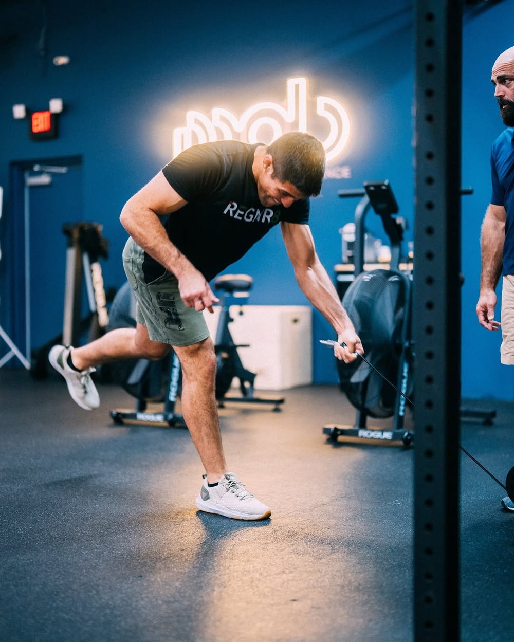 A coach guiding a member through a single-leg exercise