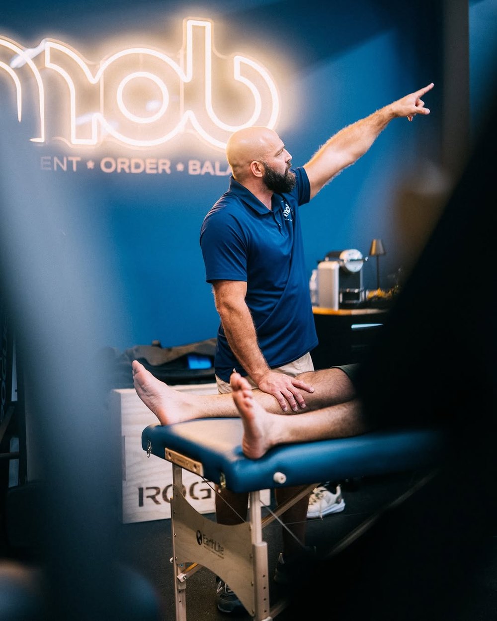 A coach working through mobility with a member under the neon mob sign